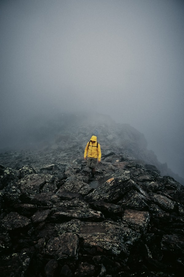 Person wearing a yellow technical shell jacket on a rocky mountain in Austria